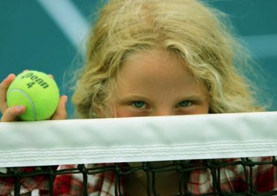 little girl on tennis court looking over net, National Tennis School