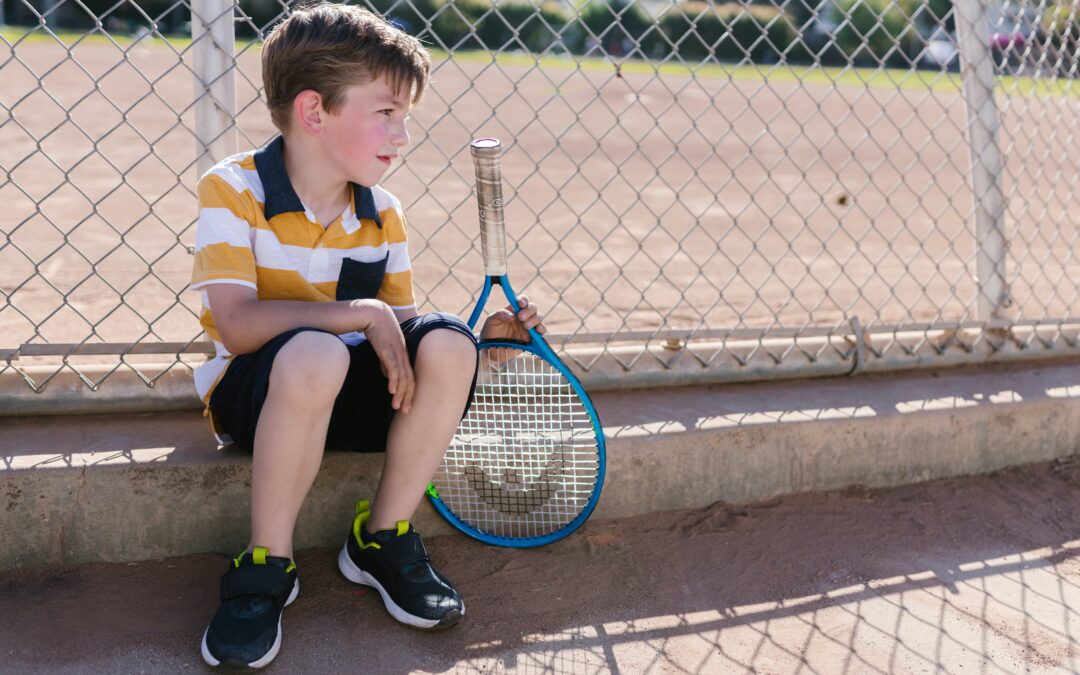Boy sitting with his tennis racquet